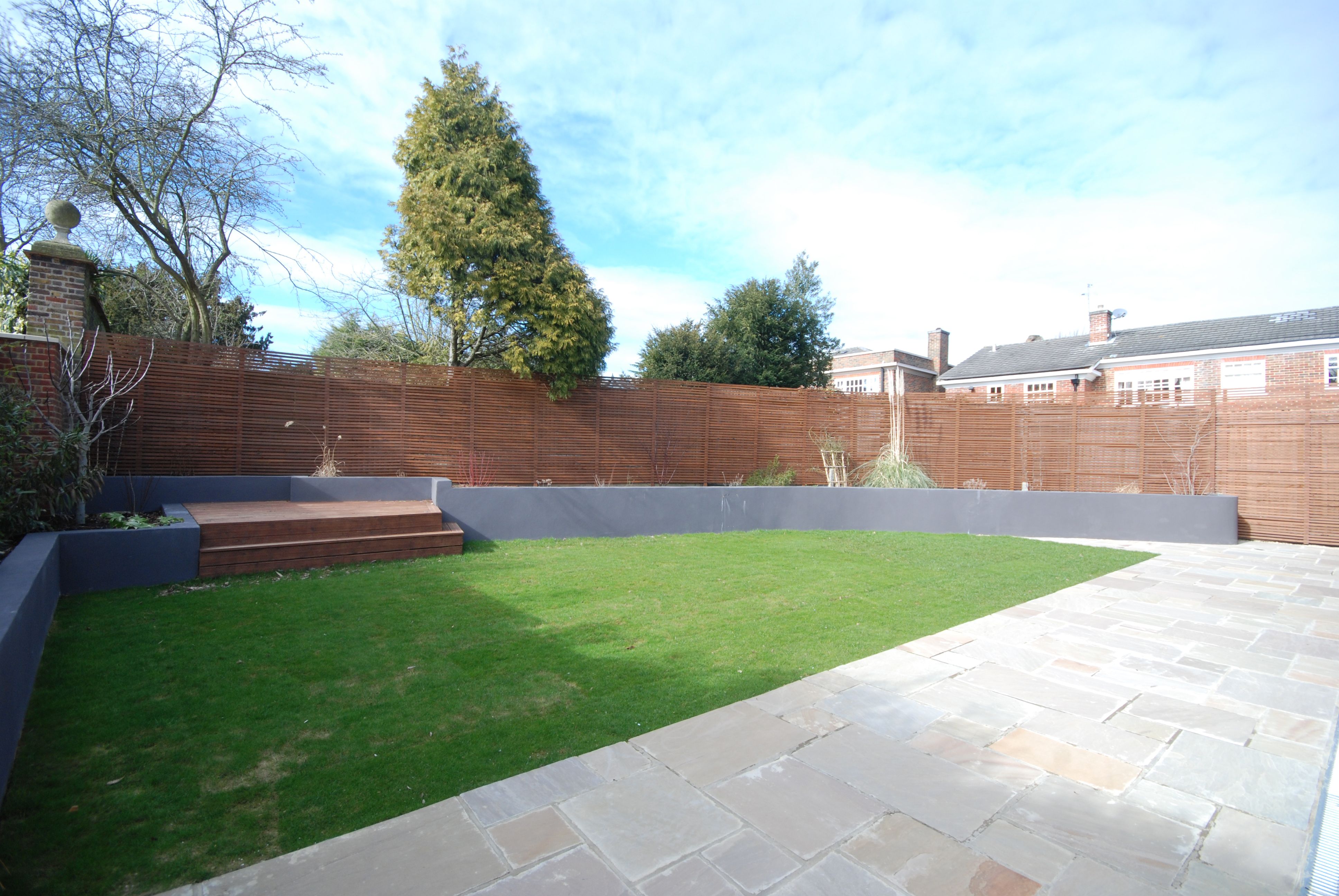 Landscaped rear garden with lawn, paved terrace and timber screening