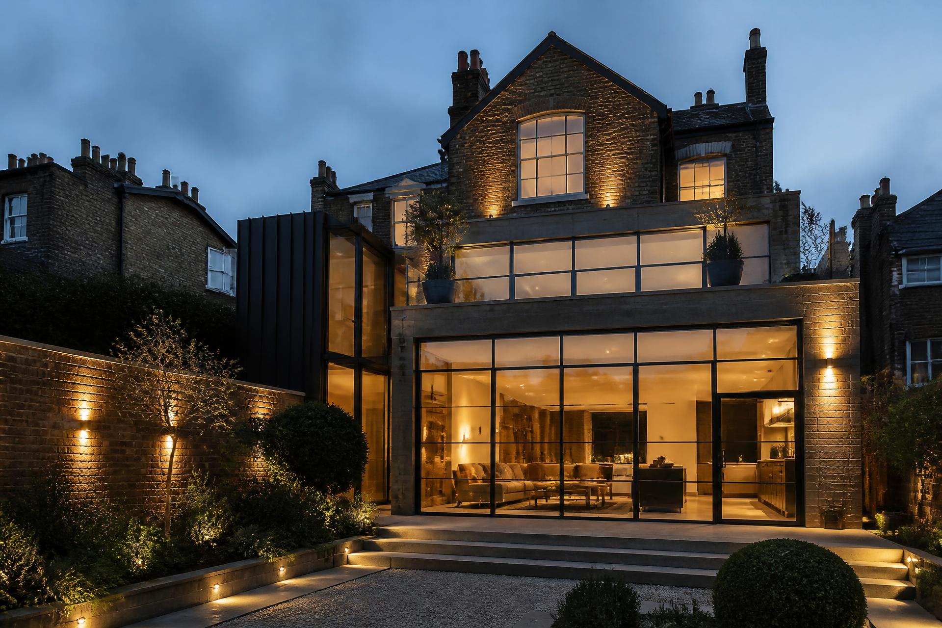 Contemporary London residential extension with steel-framed glazing lit at dusk
